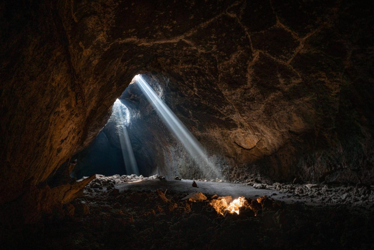 A light shines through the opening of a cave